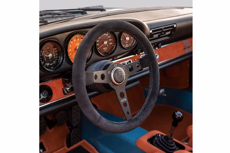 Về phần nội thất, mọi thứ vẫn giữ đúng thời kỳ sản xuất nhưng dĩ nhiên Singer cũng bổ sung một vài trang bị tiện ích để phù hợp tiêu chuẩn ngày nay hơn, ví như điều hòa không khí và hệ thống điều hướng. Cabin có rất nhiều chi tiết bọc da lộn màu cam với sọc caro màu xanh mòng két tương phản như trên ghế ngồi, ốp cửa và mặt táp lô.