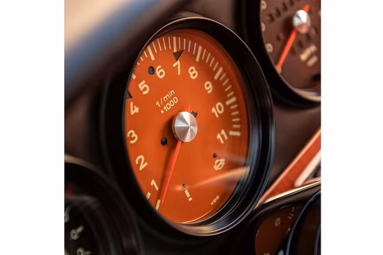 Ở những chỗ khác, chủ nhân của chiếc 911 này đã lựa chọn một bộ la-zăng phong cách Fuchs và kẹp phanh màu cam đậm với dòng chữ trắng tương phản. Ngoài ra, ngoại thất xe còn có sự hiện hữu của nắp bình nhiên liệu và bình dầu giúp gắn kết mọi thứ với nhau đẹp mắt. Theo đúng bản sắc của Singer, tất cả các thay đổi bên ngoài đã được thực hiện với mục tiêu giữ cho mọi thứ trông giống hàng nguyên bản nhất có thể.