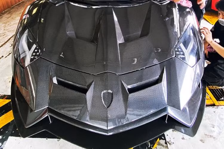 Sau gần ba tháng bắt tay vào "lột xác", chiếc Lamborghini Aventador LP700-4 độ Duke Dynamics đầu tiên ở dải đất hình chữ S đã ra lò với ngoại hình hầm hố. Cụ thể, không để chiếc Aventador LP700-4 độ Duke Dynamics này mang bộ áo sợi carbon trần, sẽ khó phối màu với lại bên hông xe cũng như nóc xe có màu vàng nguyên bản, thay vào đó, chủ nhân đã chọn cách đổi áo mới bằng đề-can với màu rằn ri rất ấn tượng và nổi bật cho bò tót này. 