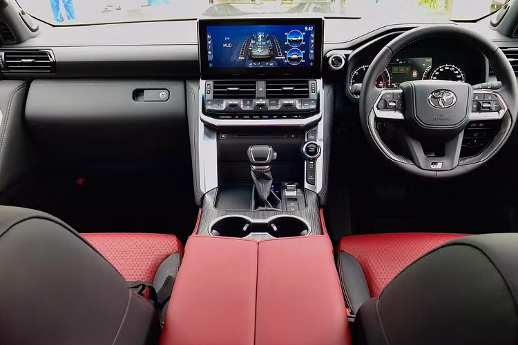 Bên trong Toyota Land Cruiser GR Sport 2022 là không gian nội thất bọc da màu đỏ phối đen tương phản. Xe có những trang bị đáng chú ý như bảng đồng hồ kết hợp giữa kỹ thuật số và analogue, vô lăng bọc da phối ốp gỗ, cần số bọc da, sạc điện thoại thông minh không dây, 2 hàng ghế trước đủ tính năng sưởi ấm/làm mát, ngăn làm mát đồ uống bên dưới bệ tì tay trung tâm hàng ghế trước, hệ thống lọc không khí Nano X...