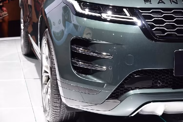 Trên đầu xe, Range Rover Evoque L 2021 được trang bị lưới tản nhiệt với mắt lưới hình tổ ong mạ crôm sang trọng. Tuy nhiên, lưới tản nhiệt này đã được tăng kích thước thêm 30% so với bản thường. Nằm hai bên lưới tản nhiệt là cụm đèn pha LED với dải đèn LED định vị ban ngày bao quanh. Thêm vào đó là khe gió khá lớn trên cản trước với 2 nan nằm ngang, sơn màu xám Premium Gray, tạo cảm giác sang trọng hơn bản thường.
