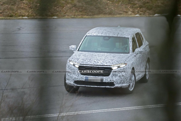 Phần đầu mẫu xe SUV Honda CR-V 2023 được trang bị lưới tản nhiệt có thiết kế giống với HR-V thế hệ mới đã trình làng tại thị trường Nhật Bản vào hồi tháng 2 vừa qua. Nói cách khác, CR-V 2023 sẽ được bổ sung phong cách thiết kế đầu xe mới của hãng Honda. Hai bên lưới tản nhiệt là cụm đèn pha mới với thiết kế sắc sảo hơn. Trong khi đó, nắp ca-pô của Honda CR-V 2023 có vẻ cao hơn, dài hơn và phẳng hơn trước, ám chỉ việc mẫu xe này sẽ được trang bị khoang động cơ cỡ lớn hơn.