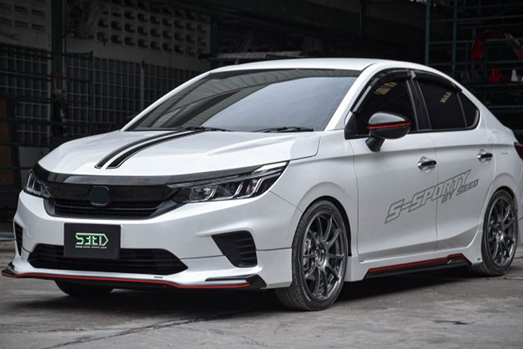 Bộ sản phẩm bodykit độ Honda City 2021 này bao gồm phần líp cản trước mới, các chi tiết màu đen và đỏ bóng, phần ốp sườn giả sợi carbon. Ốp gương chiếu hậu sơn đen cùng sọc đỏ ở giữa.