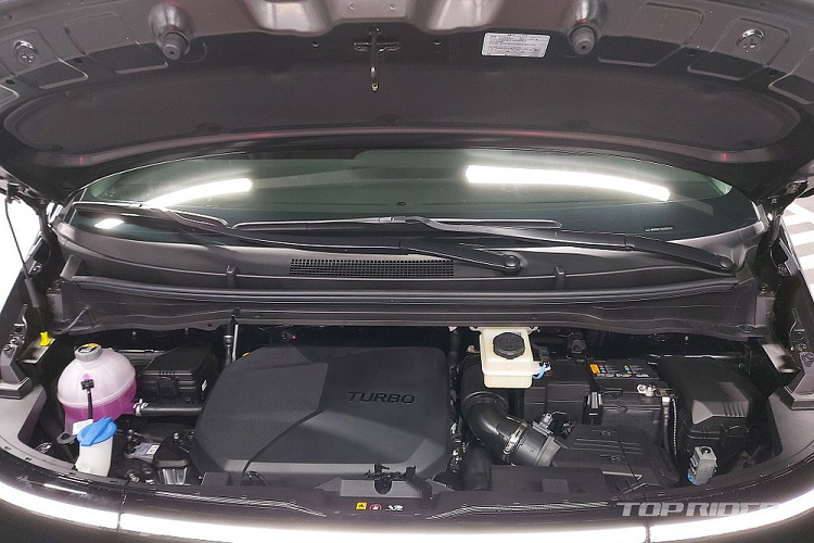 Chưa hết, chiếc Hyundai Staria Lounge AWD 7 chỗ này còn có những điểm nhấn ngoại thất màu đồng ở cản trước, lưới tản nhiệt, viền đèn pha, vành la-zăng, logo trên nắp ca-pô và cửa cốp sau cũng như tem chữ nổi "Staria".