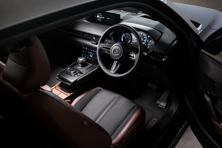 Nội thất MX-30 trang bị màn hình hiển thị thông tin lái xe TFT 7 inch, màn hình thông tin giải trí 8,8 inch tương thích Apple CarPlay và Android Auto, định vị vệ tinh,...Ghế bọc da hai tông màu với ghế trước chỉnh điện tích hợp sưởi ghế và nhớ ghế. Vô lăng có sưởi. Điều hòa trên xe loại kiểm soát khí hậu một vùng.