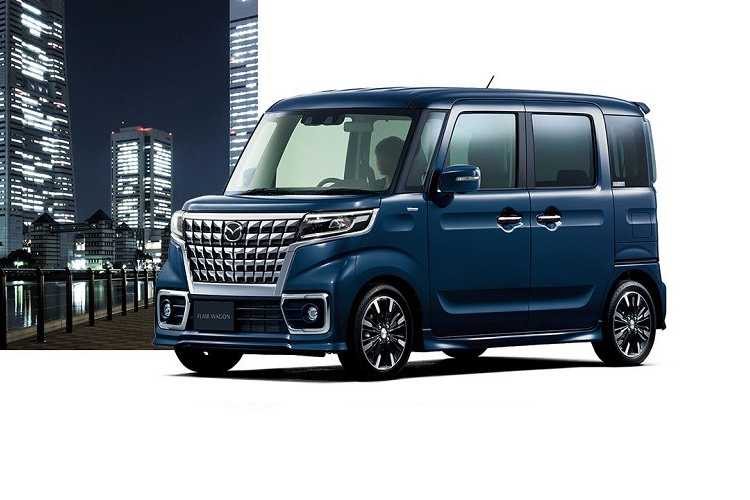 Tiếp đến là hốc gió trung tâm hình thang, đi kèm khung lắp biển số. Ở hai bên hốc gió trung tâm là đèn sương mù trước với viền mạ crôm. Khác với bản thường, Mazda Flair Wagon 2022 bản Custom được trang bị vành la-zăng sơn phối 2 màu thể thao hơn, ốp gương ngoại thất tích hợp đèn báo rẽ và tay nắm cửa mạ crôm. Bên cạnh đó, bản Custom còn có cả cánh gió mui - trang bị vốn không dành cho bản thường.