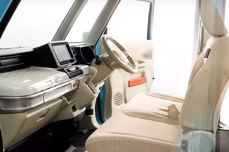 Dưới nữa là hốc gió trung tâm cỡ lớn với mắt lưới hình tổ ong màu đen và đèn sương mù hình tròn khá nhỏ ở hai bên. Hốc gió trung tâm và đèn sương mù đều được bao quanh bằng viền màu đen dày dặn. Ở bên sườn, Mazda Flair Wagon 2022 bản Tough có nẹp màu đen trên cửa, bậc cửa và vành la-zăng thể thao hơn cũng như baga nóc. Trong khi đó, ốp gương ngoại thất, tay nắm cửa và nóc đều được sơn màu đen.