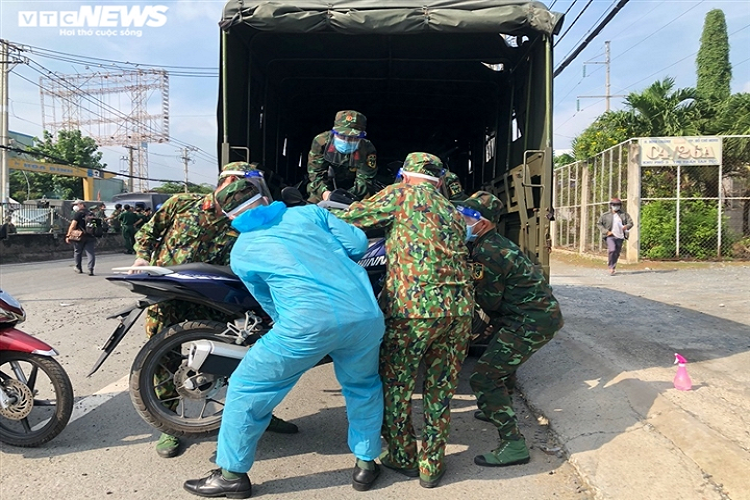 Lực lượng quân đội hỗ trợ người dân đưa xe máy lên xe chuyên dụng. Những chiếc xe máy này sẽ được quân đội chở về quê cho người dân.