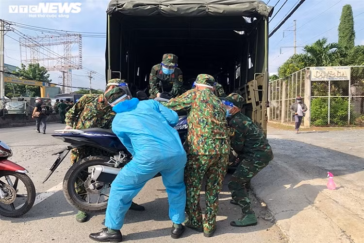 Lực lượng quân đội hỗ trợ người dân đưa xe máy lên xe chuyên dụng. Những chiếc xe máy này sẽ được quân đội chở về quê cho người dân.