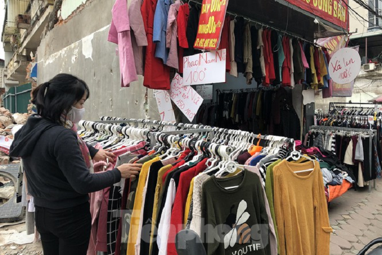 Một cửa hàng bán giảm giá. Áo phao nam nữ các loại được bán với giá 100.000 đồng/chiếc. Chị Đinh Thị Thanh Hoa (Thụy Khê, Hà Nội), người chuyên bán quần áo nhập từ Trung Quốc về chia sẻ, hiện nay, bên phía Trung Quốc cũng lạnh nên cháy hàng, khan hàng. Các mặt hàng được bày bán giảm giá, đa số là hàng tồn của năm trước. Nhờ được bảo quản tốt nên hàng vẫn còn trông mới nguyên, hơn nữa, mẫu sản phẩm từ năm trước đên thời điểm hiện nay chưa có thay đổi nhiều