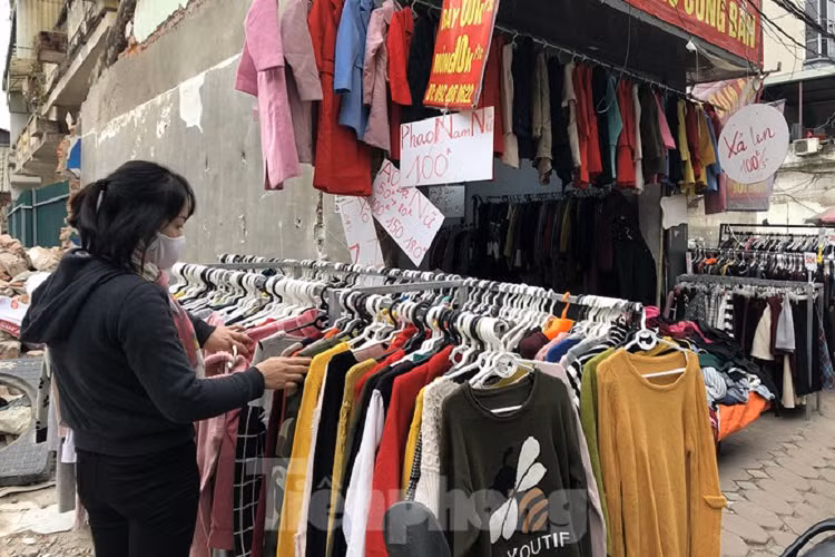 Một cửa hàng bán giảm giá. Áo phao nam nữ các loại được bán với giá 100.000 đồng/chiếc. Chị Đinh Thị Thanh Hoa (Thụy Khê, Hà Nội), người chuyên bán quần áo nhập từ Trung Quốc về chia sẻ, hiện nay, bên phía Trung Quốc cũng lạnh nên cháy hàng, khan hàng. Các mặt hàng được bày bán giảm giá, đa số là hàng tồn của năm trước. Nhờ được bảo quản tốt nên hàng vẫn còn trông mới nguyên, hơn nữa, mẫu sản phẩm từ năm trước đên thời điểm hiện nay chưa có thay đổi nhiều