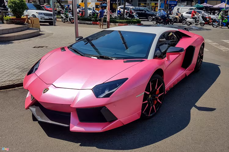 Dàn siêu xe đắt tiền lăn bánh tại TP HCM đầu tiên là Lamborghini Aventador, đây một cái tên khá quen thuộc với giới đam mê xe tại Việt Nam. Có đến hàng chục chiếc Aventador với nhiều phiên bản khác nhau có mặt trên dải đất hình chữ S. Để khiến chiếc xe mình nổi bật hơn, chủ nhân của siêu xe này đã chọn gói độ Novitec Torado cùng lớp decal màu hồng lạ mắt. 