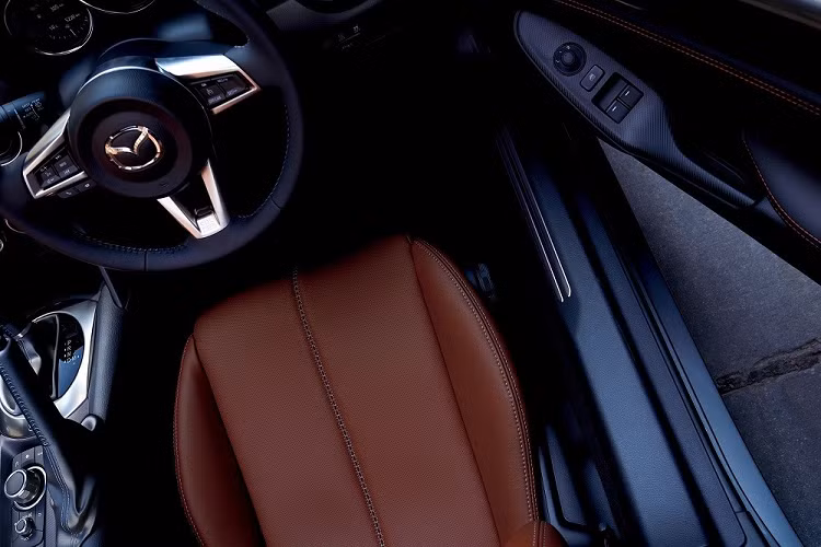 Ngoài ra, bản 990S còn được trang bị lò xo, hệ thống giảm chấn, hệ thống lái và bộ điều khiển động cơ ECU hiệu chỉnh. Những thay đổi còn lại của bản 990S bao gồm mui nỉ và viền cửa gió điều hòa màu xanh đậm. Nếu chi thêm tiền, khách hàng Nhật Bản có thể trang bị thảm sàn với chỉ thêu màu xanh đậm cho Mazda Roadster 990S 2022.