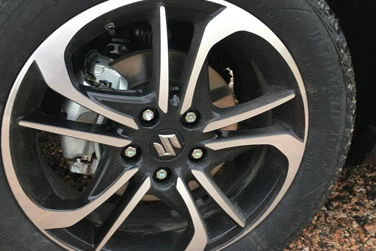 Vòng sang bên sườn, chúng ta sẽ bắt gặp nẹp thân xe bằng nhựa màu đen, hốc bánh vuông vắn, đi kèm bộ vành hợp kim với đường kính 17 inch. Tiếp đến là cụm đèn hậu ăn sâu vào bên trong cửa cốp, nối với nhau bằng nẹp màu đen ở giữa tích hợp logo của hãng Suzuki, và cánh gió mui. Trên cản sau còn có nẹp bằng nhựa màu đen, 2 hốc gió giả đi kèm đèn phản quang và tấm ốp gầm màu bạc.