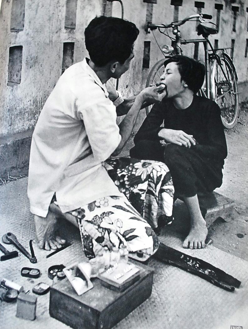 Dịch vụ cà trắng răng ngay trên vỉa hè, một hình ảnh thú vị về cuộc sống ở Việt Nam xưa. Bức ảnh này nằm trong cuốn sách có tựa đề “ Đông Dương sâu kín” (L’Indochine Profonde) của tác giả J. P. Dannaud.