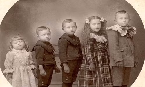 Bé gái (trái ảnh) đã qua đời và được dựng đứng lên nhờ dụng cụ đặc biệt khi chụp ảnh với những người anh chị em.