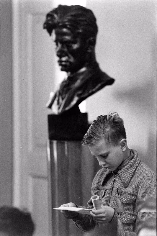 Một cậu bé người Liên Xô chăm chú đọc nội dung viết trên tờ giấy.