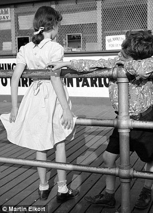 Một bé trai và bé gái dựa vào lan can chơi.