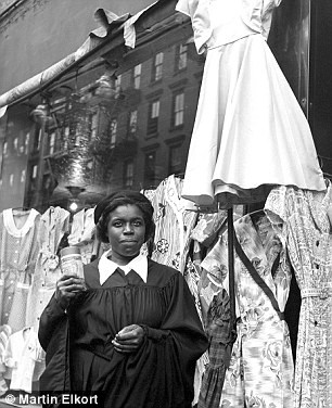 Một phụ nữ da màu đứng trước cửa hàng bán quần áo.