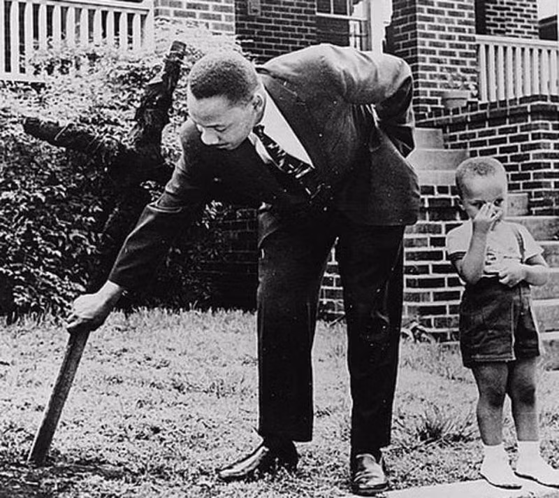 Martin Luther King Jr. cùng với con trai dọn một cây thập thánh giá ở sân trước nhà năm 1960. Cây thánh giá này bị đốt được cho là do người thường tấn công nhằm vào gia đình vị mục sư này.