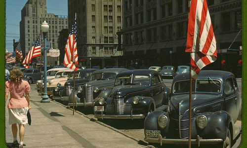 Thiếu nữ Mỹ đi bộ trên đường phố ở Lincoln, bang Nebraska. Những ô tô đậu thẳng hàng hai bên đường.