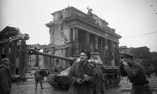 Nhiếp ảnh gia Hồng quân Liên Xô Yevgeny Khaldei (ở giữa ảnh) tác nghiệp ở Berlin. Ông di chuyển cùng binh sĩ Liên Xô và ghi nhận tình hình chiến sự ở gần công Brandenburg hồi tháng 5/1945. Nhiều công trình ở Berlin bị phá hủy nghiêm trọng sau khi Chiến tranh thế giới 2 kết thúc. Hậu quả của Chiến tranh thế giới 2 khiến nhiều người chết, nhiều gia đình ly tán, mất nhà cửa, kinh tế đi xuống...