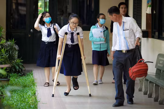 Hình ảnh người cha từ Bình Chánh đưa con gái đi thi tại cụm thi trường THPT Nguyễn Văn Luông (quận 6, TP. HCM) được nhiều người chú ý. Kim Tuyến không may bị tai nạn ở chân và tạm thời chỉ có thể đi lại bằng nạng. Tuy nhiên, nữ sinh vẫn quyết tâm đạt điểm số cao trong kỳ thi THPT quốc gia 2017. Ảnh: Người lao động.