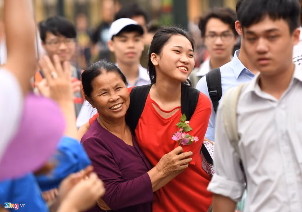 Bà Đề từ Bắc Giang lên thủ đô chăm cháu thi THPT quốc gia. Sau khi thí sinh làm xong bài môn Toán, bà ôm chầm, tặng cháu Nguyễn Thị Thanh Xuân đóa hoa giấy tại cổng trường, khiến cô gái xúc động suýt khóc. Ảnh: Tiến Tuấn.