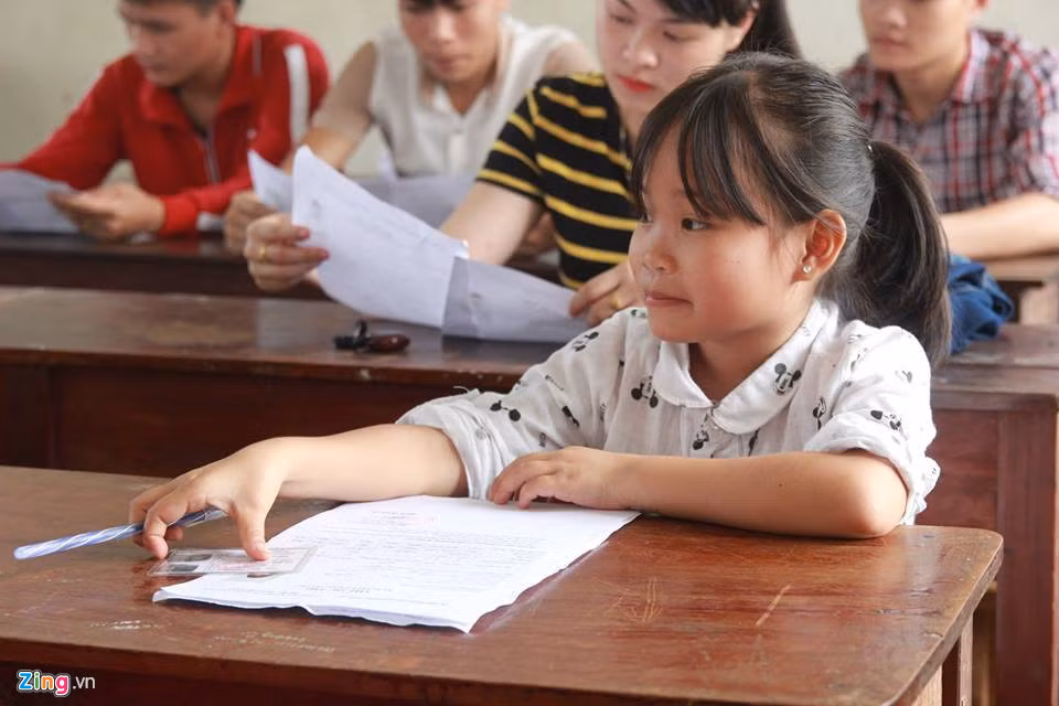 Ngồi lọt thỏm giữa các bạn cùng trang lứa, Lô Thị Bé (trường THPT Quế Phong, Nghệ An) chỉ cao 1,14 m, nặng 22 kg. Nữ sinh có gương mặt dễ mến như học sinh cấp một tạo ra một hình ảnh thú vị, đặc biệt cho mùa thi 2017. Ảnh: Phạm Hòa.