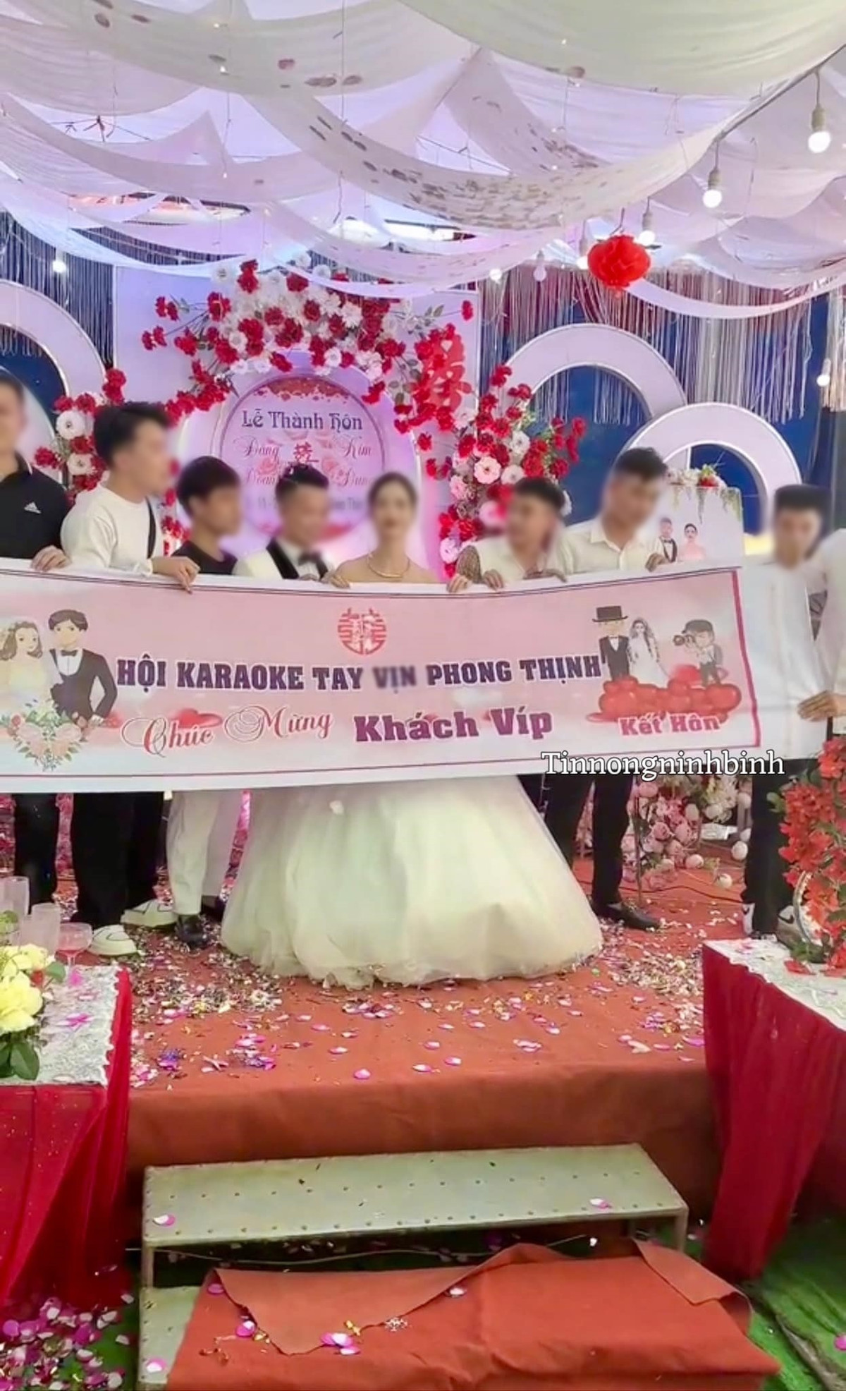 Hình ảnh một nhóm 5-6 thanh niên lên chụp hình kỉ niệm với cô dâu chú rể cùng băng rôn in dòng chữ "Hội karaoke tay vịn An Thịnh chúc mừng khách VIP kết hôn".