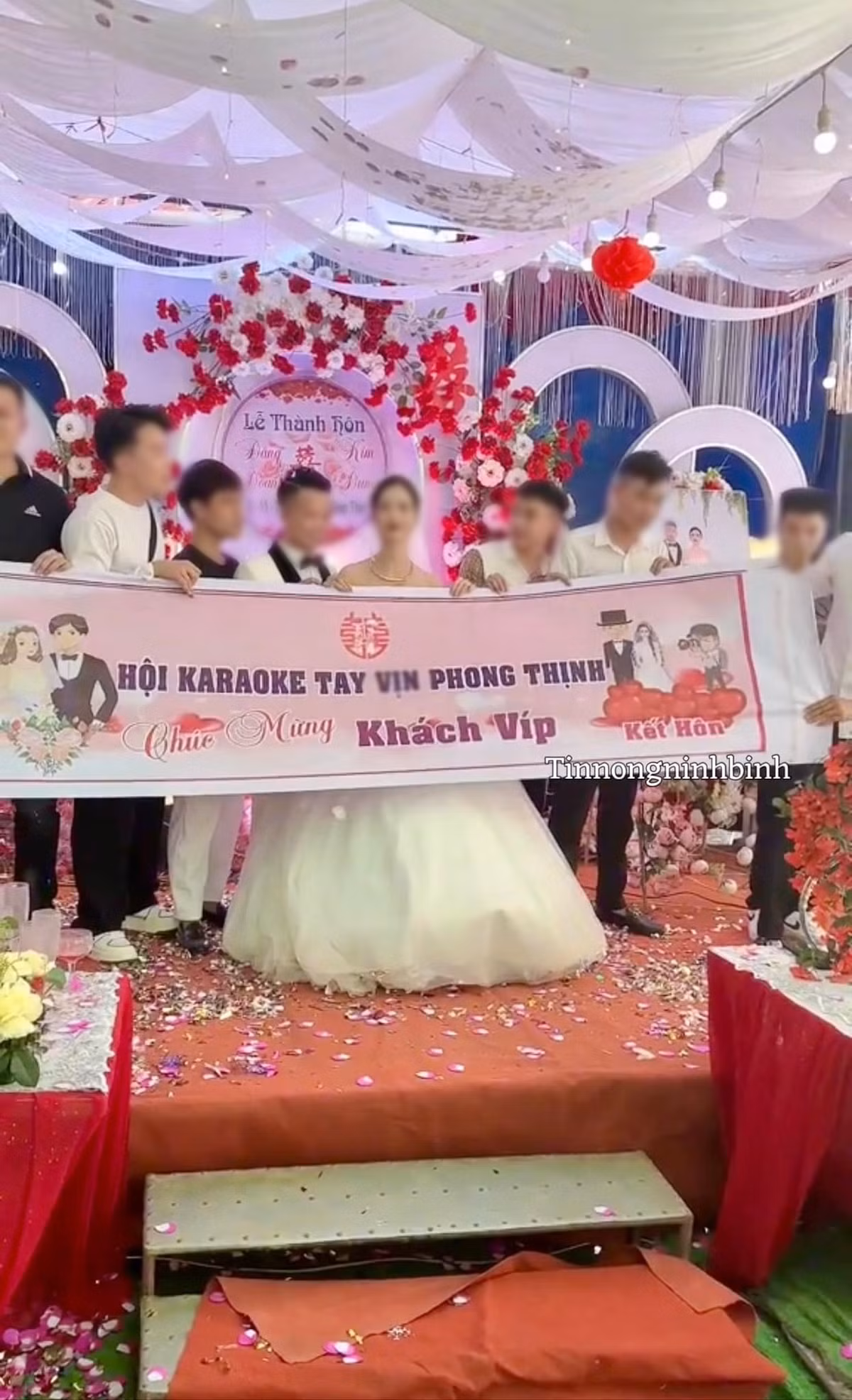 Hình ảnh một nhóm 5-6 thanh niên lên chụp hình kỉ niệm với cô dâu chú rể cùng băng rôn in dòng chữ "Hội karaoke tay vịn An Thịnh chúc mừng khách VIP kết hôn".