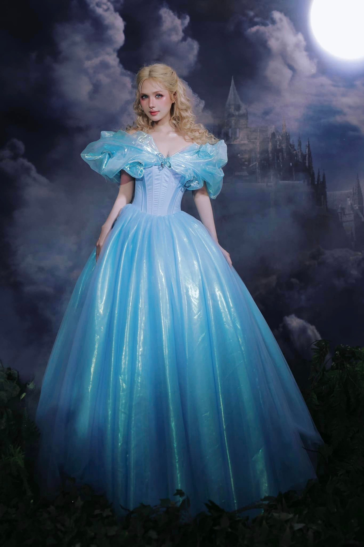 Trong tạo hình lần này, Xoài Non vô cùng đầu tư khi lựa chọn thiết kế váy màu xanh với phần eo ôm sát, phần chân váy xòe rộng. Cô nàng lựa chọn lối make-up tone hồng nhấn vào mắt, kết hợp cùng mái tóc vàng xoăn sóng tựa như búp bê.