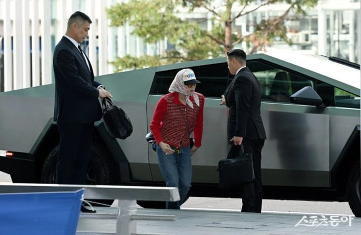 Nam ca sĩ xuất hiện tại sân bay Incheon lên đường đến Hồng Kông tham dự show diễn diễn thời trang của Chanel với tư cách đại sứ thương hiệu. Thủ lĩnh Big Bang gây chú ý với phong cách phối đồ unisex lạ lẫm. Anh diện áo len ca rô tone đỏ, đeo túi Chanel hình quả trám cỡ lớn và lăng xê triệt để mốt trùm khăn kết hợp mũ phớt in hình tên ca khúc mới. (Ảnh: @dispatch_style).