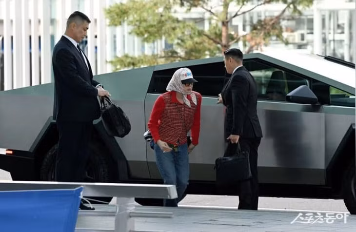 Nam ca sĩ xuất hiện tại sân bay Incheon lên đường đến Hồng Kông tham dự show diễn diễn thời trang của Chanel với tư cách đại sứ thương hiệu. Thủ lĩnh Big Bang gây chú ý với phong cách phối đồ unisex lạ lẫm. Anh diện áo len ca rô tone đỏ, đeo túi Chanel hình quả trám cỡ lớn và lăng xê triệt để mốt trùm khăn kết hợp mũ phớt in hình tên ca khúc mới. (Ảnh: @dispatch_style).