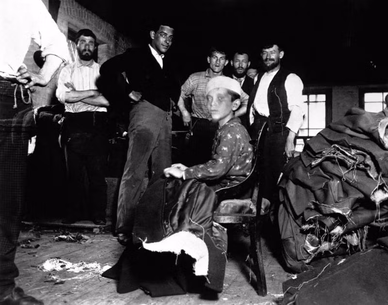 Cậu bé làm việc trong xưởng may ở khu ổ chuột, 1889. Ảnh: Jacob Riis.