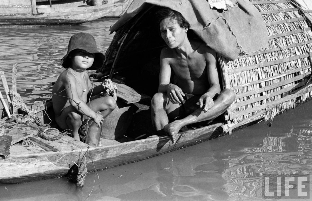 Hai cha con dân xóm chài trên một con thuyền. Ảnh: Carl Mydans/ Life.