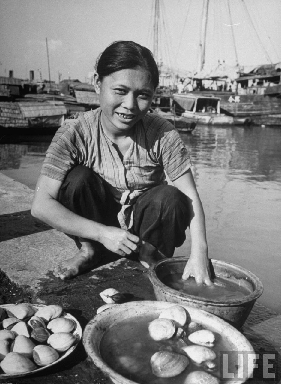 Người phụ nữ bán những con trai bên bến sông. Ảnh: Carl Mydans/ Life.