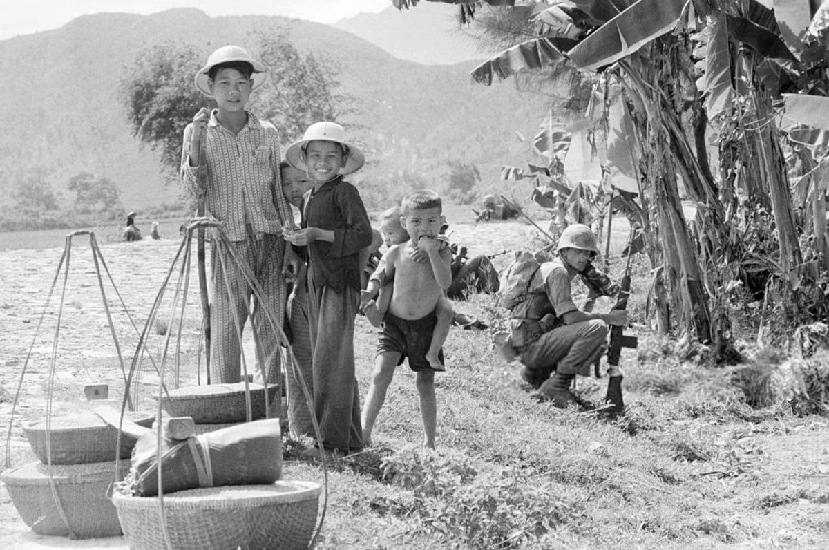 Những đứa trẻ đứng gần nhóm lính Mỹ khi họ thực hiện chiến dịch càn quét một ngôi làng, 18/7/1965. Ảnh: Jean-Claude Sauer.