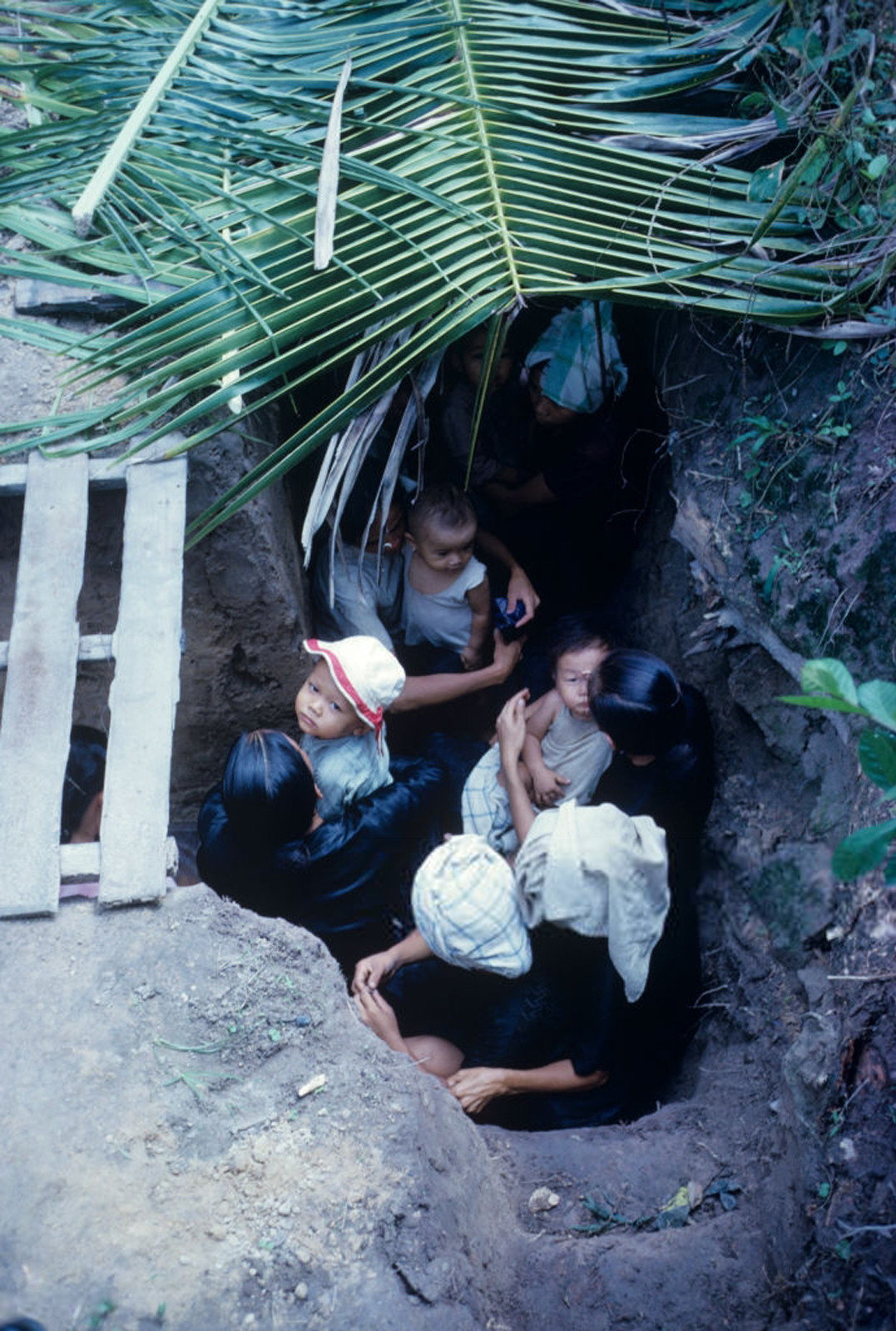 Phụ nữ và trẻ em trú ẩn dưới đường hào ở vùng chiến sự. Ảnh: Jean-Claude Sauer.