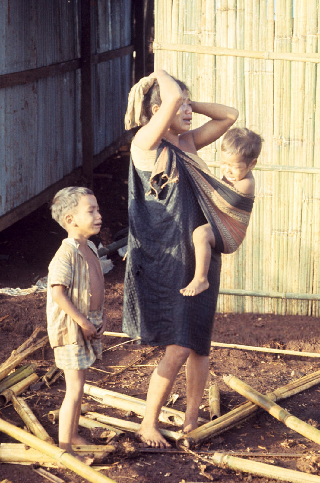 Bà mẹ người Thượng và hai đứa con khóc lóc khi chứng kiến bản làng bị tàn phá. Ảnh: Jean-Claude Sauer.