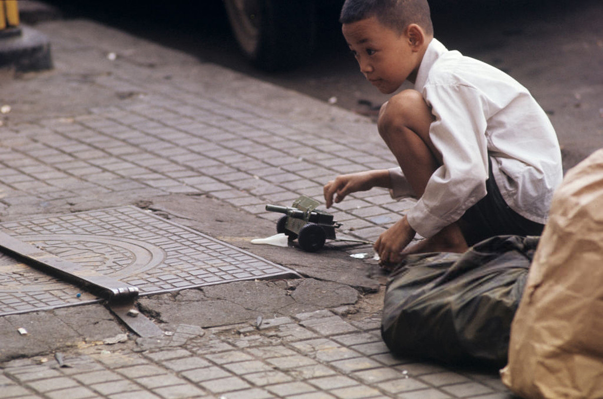 Một cậu bé chơi với một chiếc xe tăng nhỏ. Ảnh: Patrice Habans.