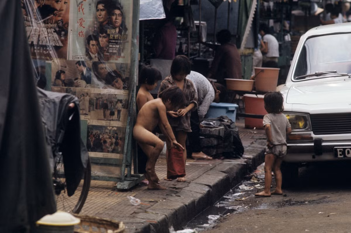 Trẻ em đường phố tụ họp trên vỉa hè Sài Gòn, cạnh chiếc xe hơi Peugeot 504. Ảnh: Patrice Habans.