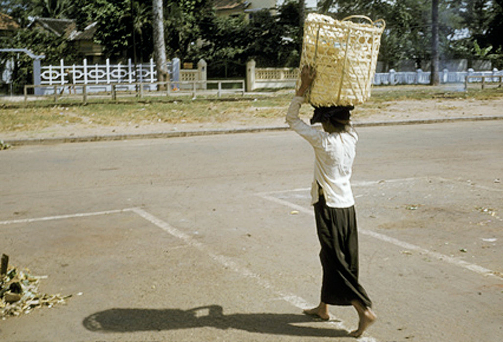 Người phụ nữ bên giỏ hàng khi chợ tan trên đường Hùng Vương, sau chợ An Đông, khu vực Chợ Lớn. Ảnh: Richard C. Harris.