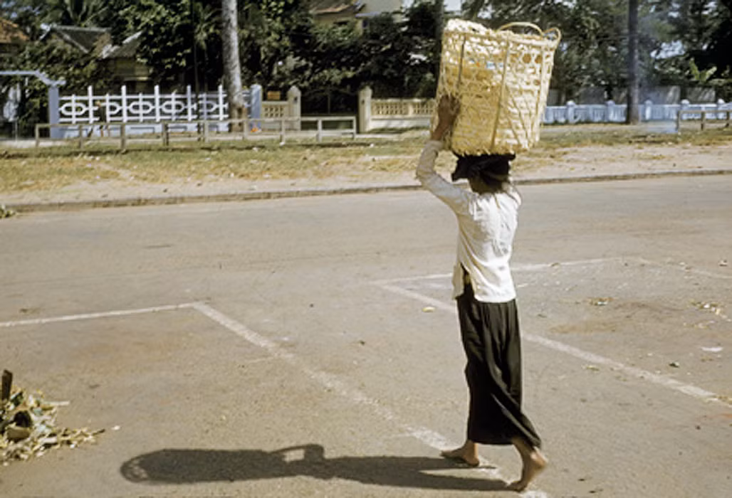 Người phụ nữ bên giỏ hàng khi chợ tan trên đường Hùng Vương, sau chợ An Đông, khu vực Chợ Lớn. Ảnh: Richard C. Harris.
