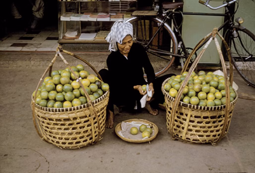 Cụ bá bán cam ngồi bóc vỏ cam bên vỉa hè. Ảnh: Richard C. Harris.