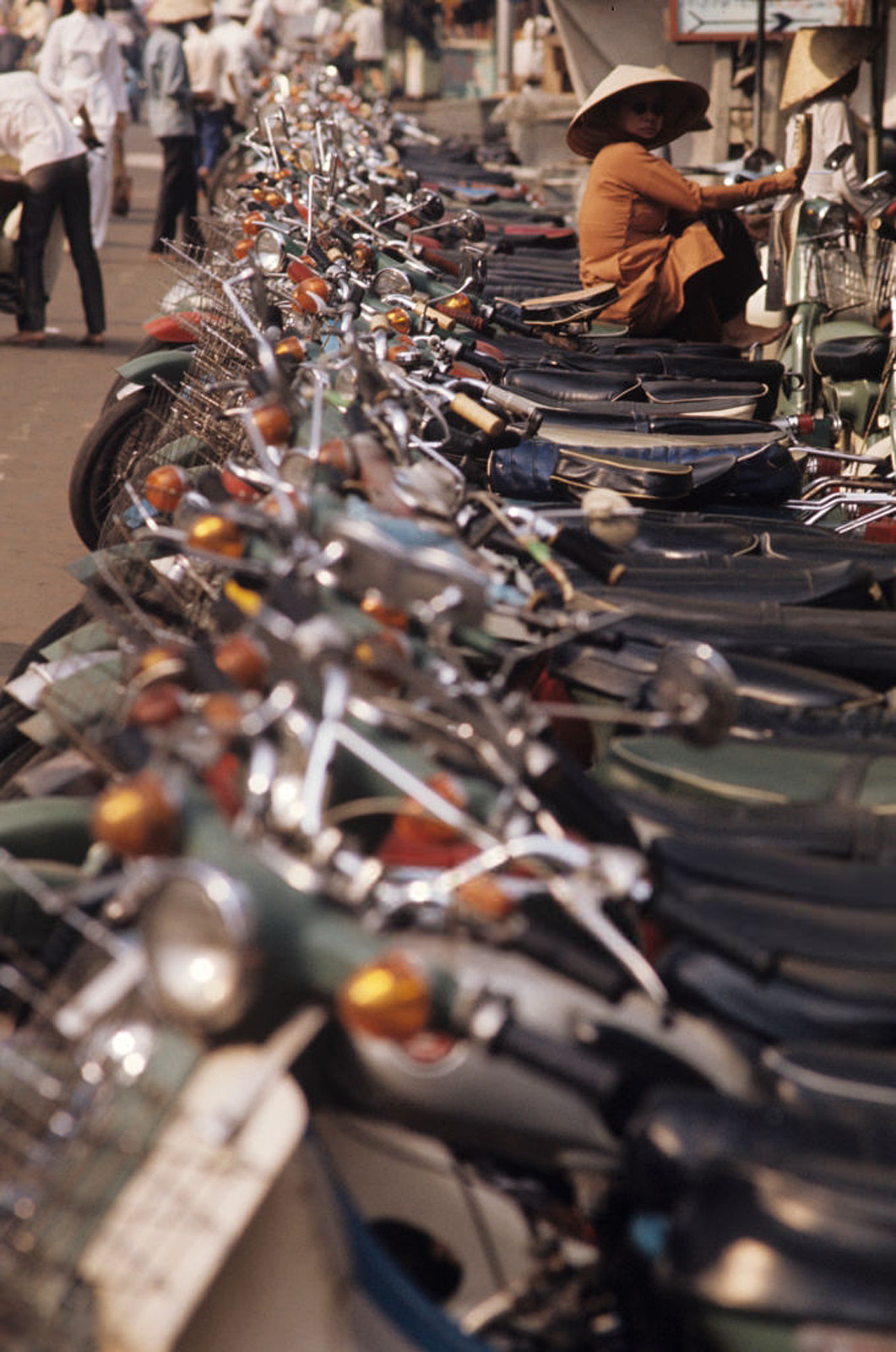 Người phụ nữ Sài Gòn ngồi trên một chiếc xe ở bãi xe hai bánh. Có lẽ bà là người trông xe. Ảnh: Patrice Habans.