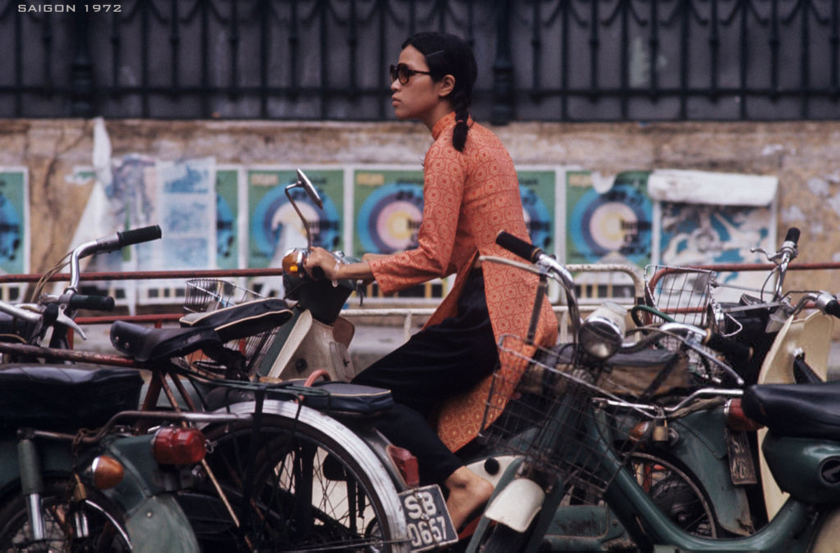 Sự kết hợp thú vị giữa truyền thống và hiện đại: Cô gái Sài Gòn mặc áo dài, đeo kính mát, ngồi trên xe Honda tại một bãi giữ xe hai bánh. Ảnh: Patrice Habans.