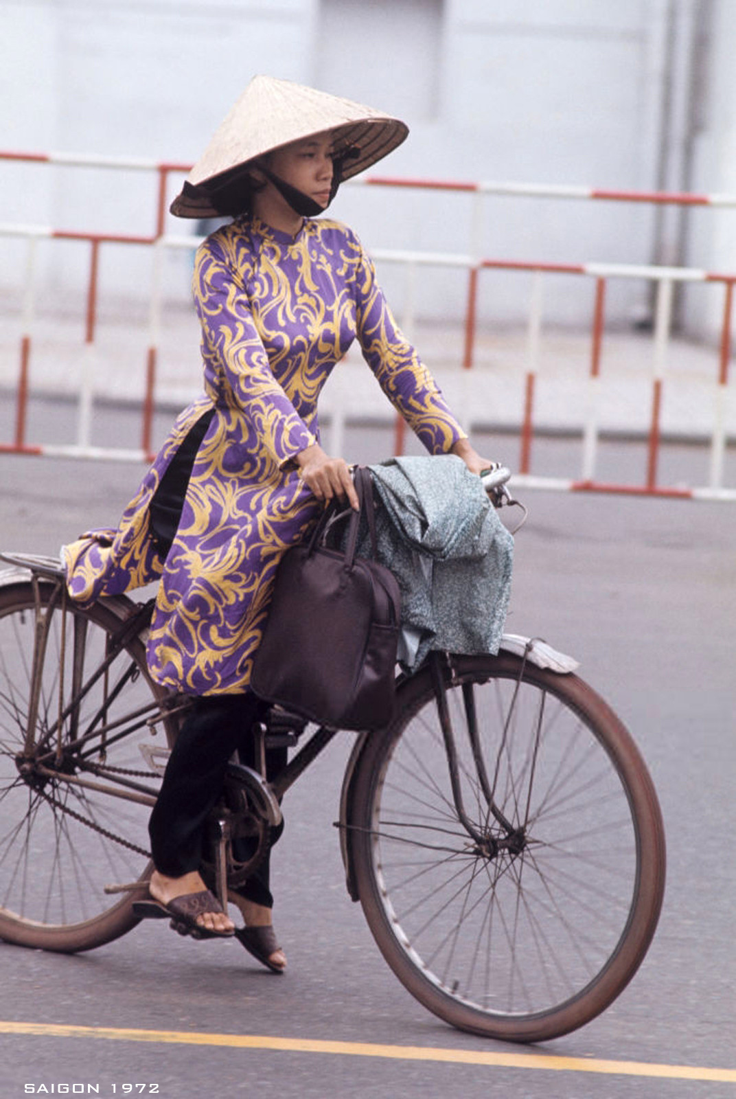 Dáng vẻ tất bật của một phụ nữ mặc áo dài đạp xe đạp, trên ghi đông lỉnh kỉnh đồ đạc. Ảnh: Patrice Habans.