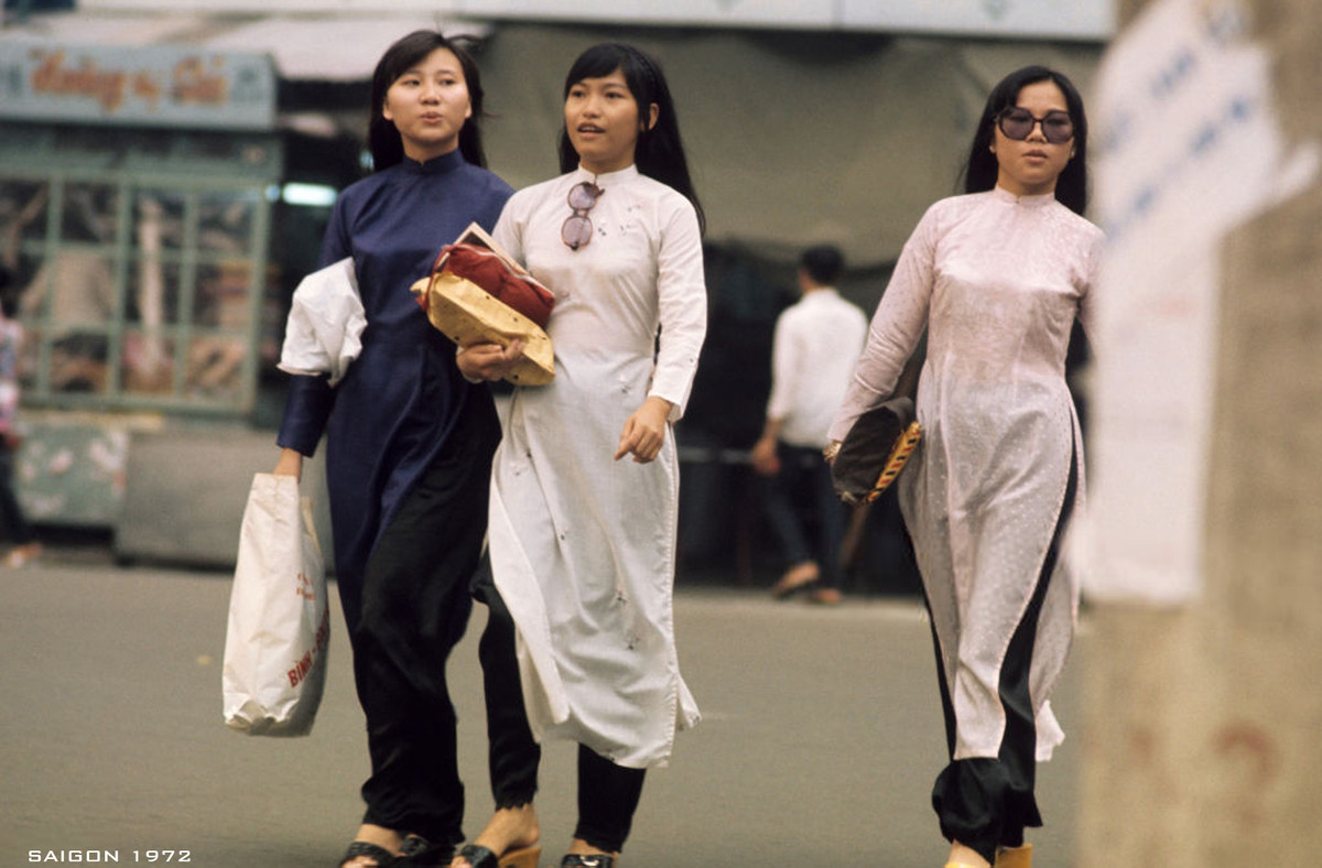 Ba thiếu nữ áo dài rảo bước trên phố sau chuyến mua sắm, trong tay cầm những bọc đồ được gói ghém cẩn thận. Ảnh: Patrice Habans.