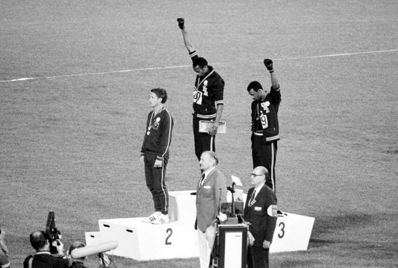 Hai vận động viên Mỹ Tommie Smith và John Carlos giành huy chương vàng và đồng trong bộ môn chạy 200 mét tại Olympic 1968. Họ đã cúi đầu, giơ tay đeo găng đen, từ chối chào cờ Mỹ và hát quốc ca để biểu lộ sự phản kháng với nạn phân biệt chủng tộc ở Mỹ. Ảnh: The Atlantic.